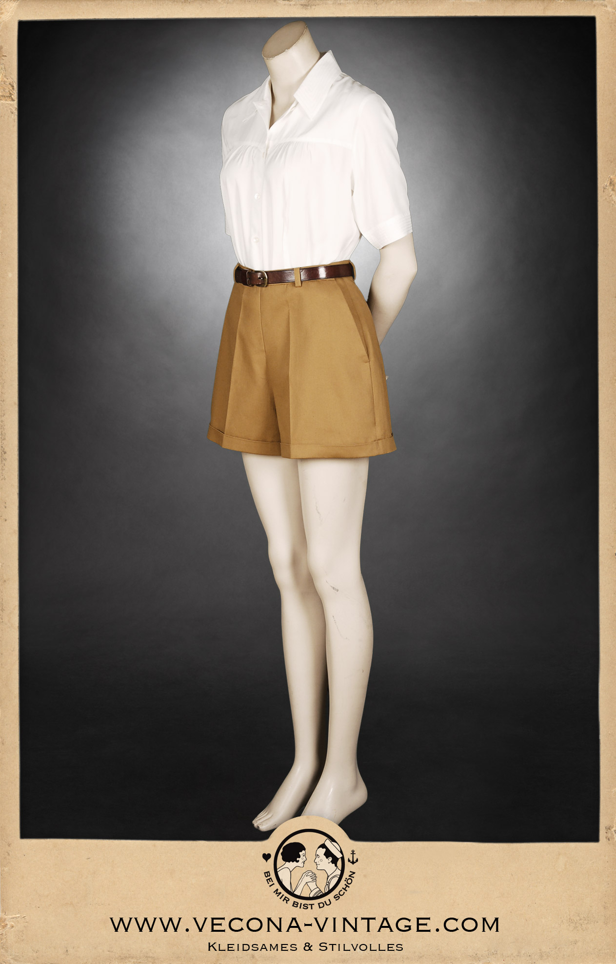 Klassische 1940er Jahre Damen-Shorts in Camel-Braun mit hohem Bund, weitem Bein und markanten Saum-Aufschlägen, kombiniert mit einer weißen Bluse und Ledergürtel. Komplettansicht der Vorderseite.