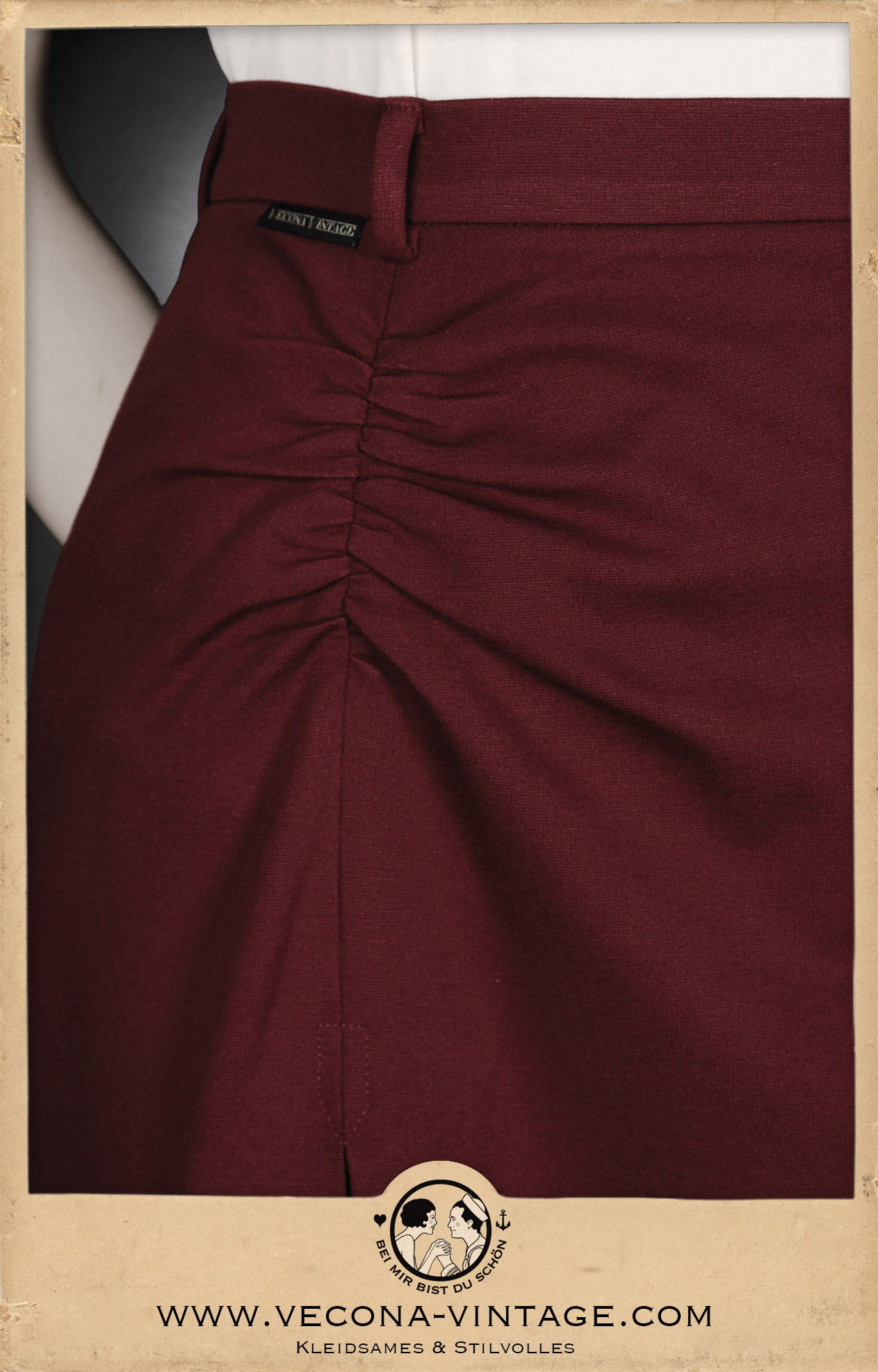 Detail view of the flattering front shirring above the high slit at the 1940s high waist pencil skirt Apache in dark red.