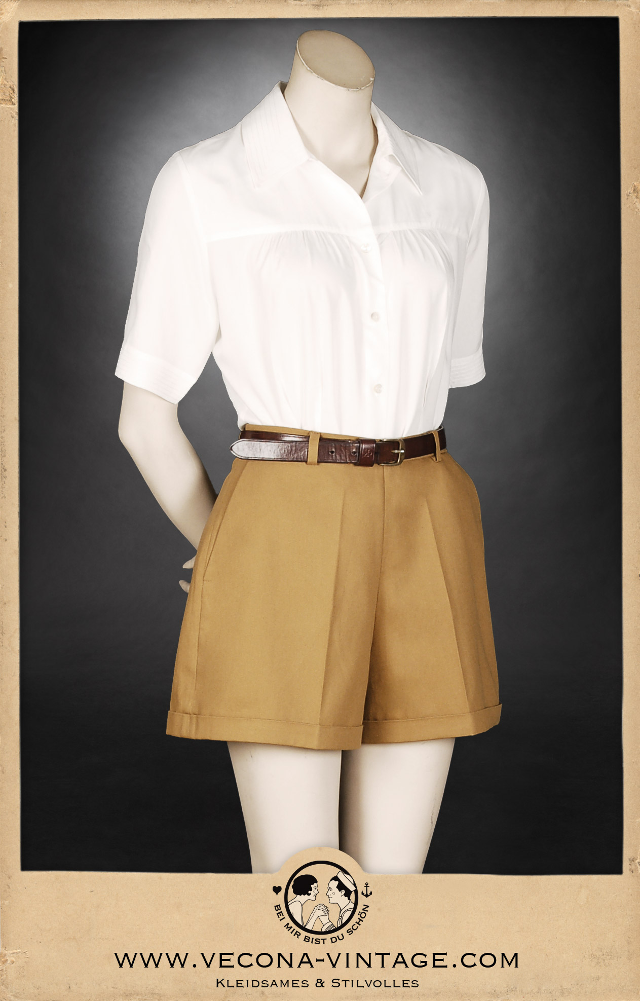 Klassische 1940er Jahre Damen-Shorts in Camel-Braun mit hohem Bund, weitem Bein und markanten Saum-Aufschlägen, kombiniert mit einer weißen Bluse und Ledergürtel. Ansicht der Vorderseite.
